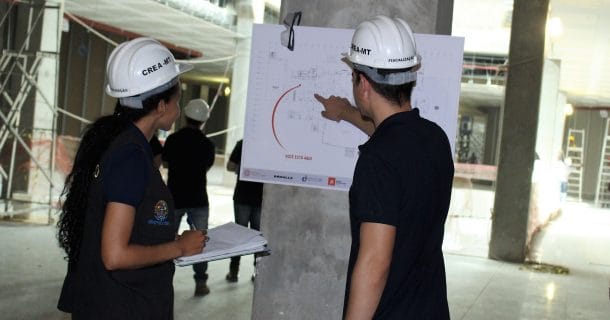homem e mulher do crea vistoriando uma obra e analisando planta