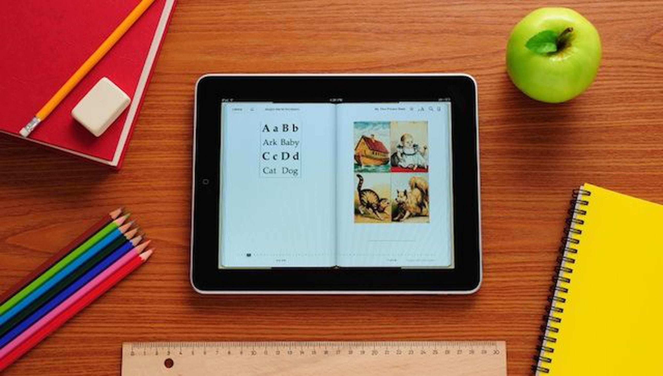 iPad em cima de mesa de professor, com agenda, maçã e lápis