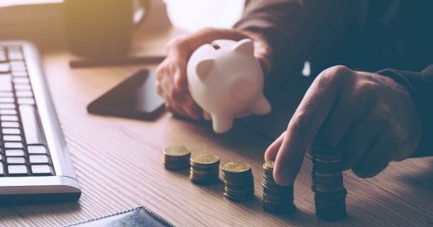 pessoa contando moedas e colocando em um cofrinho