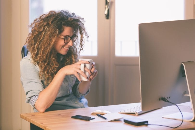 mulher em mesa com computador sorrindo