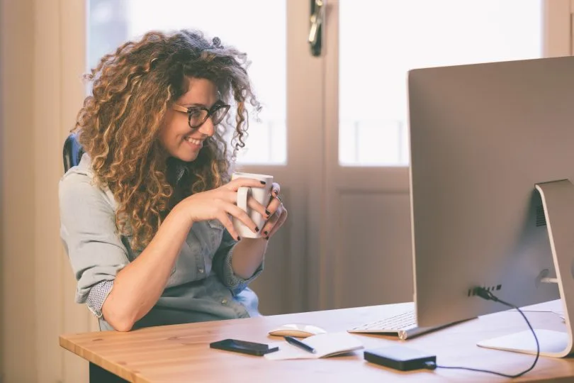 mulher em mesa com computador sorrindo