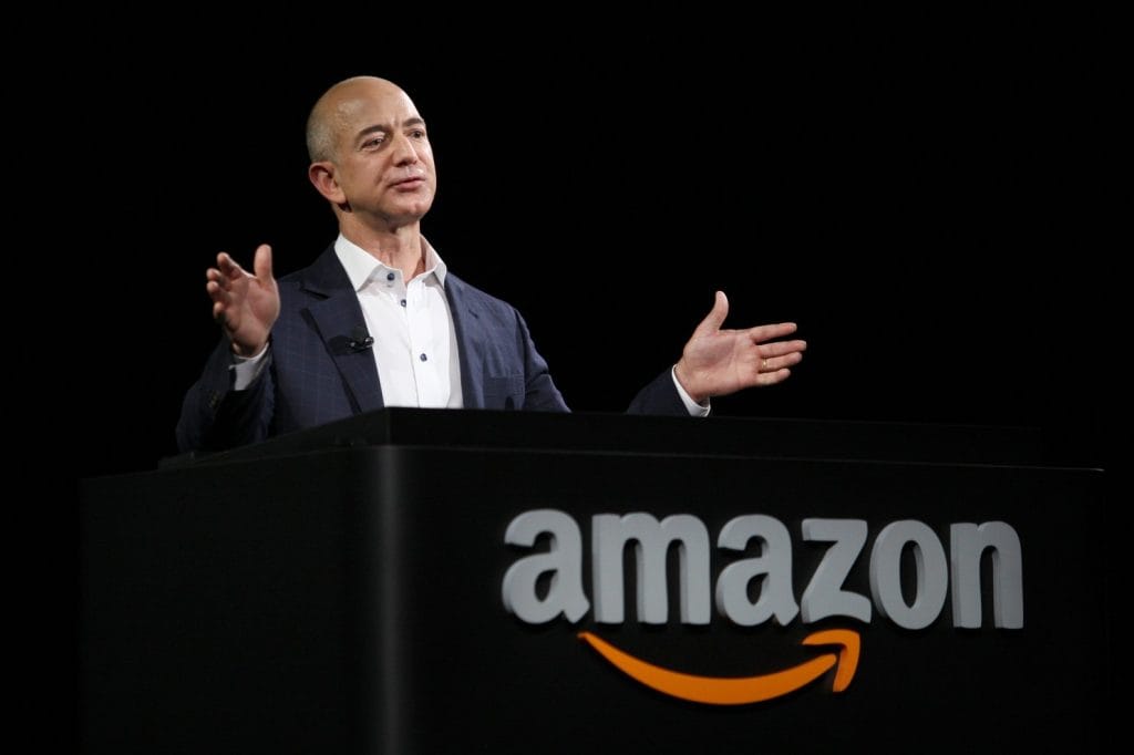 Jeff Bezos em pé atrás de estande da Amazon