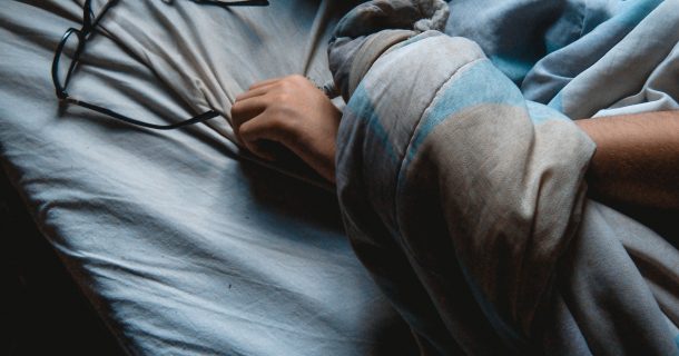 Dormir - imagem pessoa dormindo com as mãos próximas aos óculos