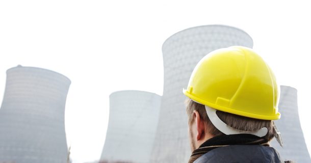 Homem de capacete olhando uma usina nuclear