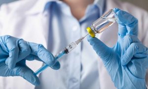 A foto mostra um profissional da saúde segurando uma seringa que, de maneira ilustrativa, contém a vacina contra a Covid-19.