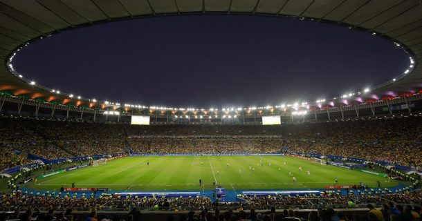 Imagem mostra a vista interior do estádio Maracanã, um dos estádios brasileiros sustentáveis. Nela é possível observar as arquibancadas com diversos torcedores e também o gramado bastante verde do campo.
