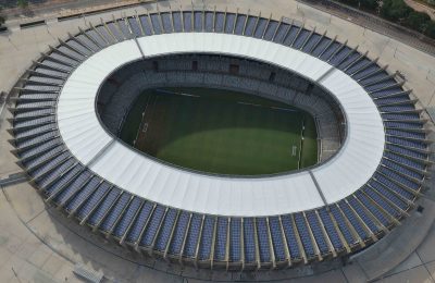 Vista superior do estádio Mineirão. Na imagem é possível enxergar o gramado verde do campo no centro e também os módulos fotovoltaicos na cobertura.