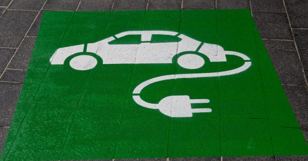 imagem de parada de veículos elétricos para abastecimento. Carro elétrico pintado de branco em retângulo verde no chão