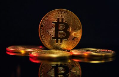 Moeda de criptomoeda dourada em superfície escura, representando a engenharia por trás do Bitcoin.
