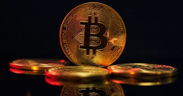 Moeda de criptomoeda dourada em superfície escura, representando a engenharia por trás do Bitcoin.