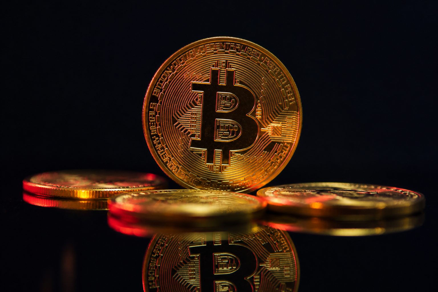 A engenharia por trás do Bitcoin: como funciona a rede que nunca parou Moeda de criptomoeda dourada em superfície escura, representando a engenharia por trás do Bitcoin.