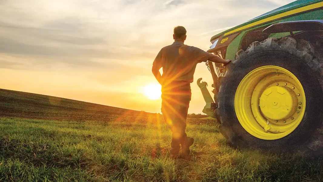 John Deere transforma dados da fazenda em conversa com novo assistente de IA Agricultor ao lado de trator John Deere em uma lavoura